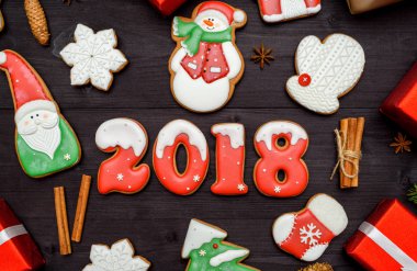 Mutlu yeni yıl 2018 işareti simgesi kırmızı ve beyaz gingerbread çerezleri üzerinde koyu ahşap arka plan, kopya alanı ile. Üstten Görünüm, düz yatıyordu. Noel kurabiyeleri, santa, kardan adam, kar tanesi, tarçın. boş alan