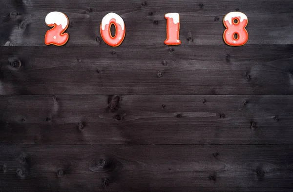 Šťastný nový rok 2018 znaménko z červených a bílých perníčky na tmavé dřevěné pozadí, kopírování prostor. Vánoční pozadí, volné místo. Pohled shora, plochá ležel — Stock fotografie