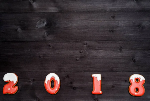 Bonne année 2018 signe symbole de biscuits au pain d'épice rouge et blanc sur fond de bois foncé, espace de copie. Fond de Noël, espace libre. Vue de dessus, plan plat — Photo