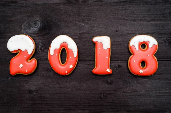 Šťastný nový rok 2018 znaménko z červených a bílých perníčky na tmavé dřevěné pozadí, kopírování prostor. Pohled shora, plochá ležel — Stock fotografie