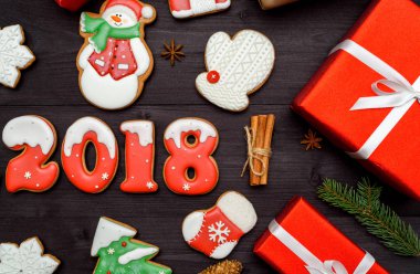 Mutlu yeni yıl 2018 işareti simgesi kırmızı ve beyaz gingerbread çerezleri üzerinde koyu ahşap arka plan, kopya alanı ile. Üstten Görünüm, düz yatıyordu. Noel kurabiyeleri, santa, çam ağacı, kar tanesi, tarçın. boş alan