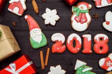 Mutlu yeni yıl 2018 işareti simgesi kırmızı ve beyaz gingerbread çerezleri üzerinde koyu ahşap arka plan, kopya alanı ile. Üstten Görünüm, düz yatıyordu. Noel çerezleri, Noel Baba, kardan adam, kar tanesi, tarçın, boş alan
