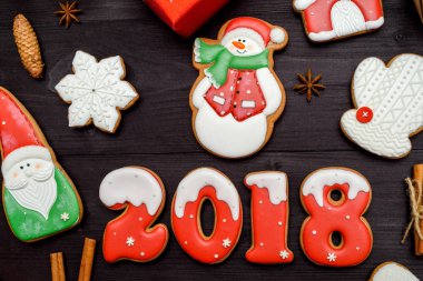 Mutlu yeni yıl 2018 işareti simgesi kırmızı ve beyaz gingerbread çerezleri üzerinde koyu ahşap arka plan, kopya alanı ile. Üstten Görünüm, düz yatıyordu. Noel kurabiyeleri, santa, kardan adam, kar tanesi, tarçın. boş alan