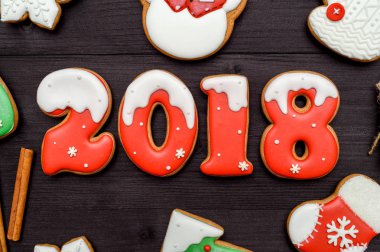 Mutlu yeni yıl 2018 işareti simgesi kırmızı ve beyaz gingerbread çerezleri üzerinde koyu ahşap arka plan, kopya alanı ile. Üstten Görünüm, düz yatıyordu. Noel kurabiyeleri, boş alan