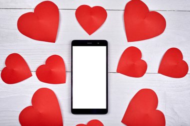 Ahşap zemin, kopya alanı üzerine kırmızı kağıt yürekleri app sunu için boş beyaz ekran ile mobil akıllı telefon yakın çekim. Düz yatıyordu, en iyi görünüm. Sevgililer uygulama şablonu sahte 