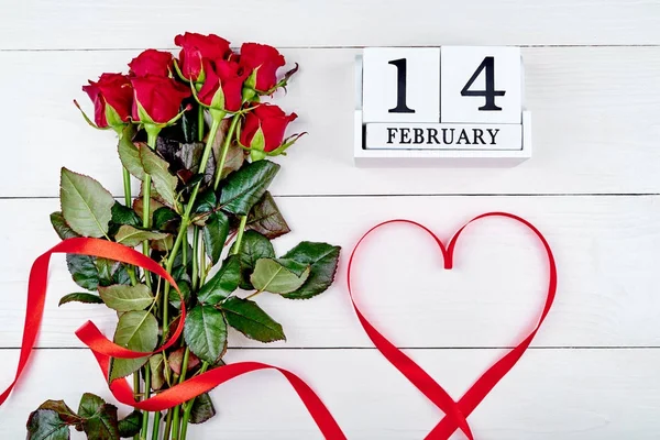 赤いバラの花束 日木製ブロック カレンダー コピー スペースとして形リボンと白い木製バレンタインデー背景 グリーティング カードのモックアップ 愛の概念 上面図 フラット — ストック写真