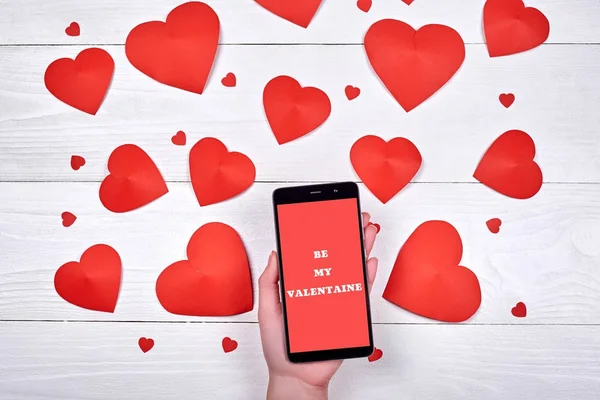 Mobil akıllı telefon işareti ile ahşap arka plan, kopya alanı üzerinde kadın el ve kırmızı Kağıt kalpleri benim sevgilim olmak kapatın. Düz yatıyordu, en iyi görünüm. Sevgililer günü uygulama şablonu sahte 