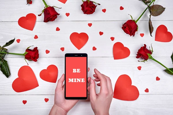 İşareti ile mobil akıllı telefon benim kadın el, kırmızı Kağıt kalpleri ve ahşap zemin, kopya alanı üzerine gül çiçek olacak kadar yakın. Düz yatıyordu, en iyi görünüm. Sevgililer günü uygulama şablonu sahte 