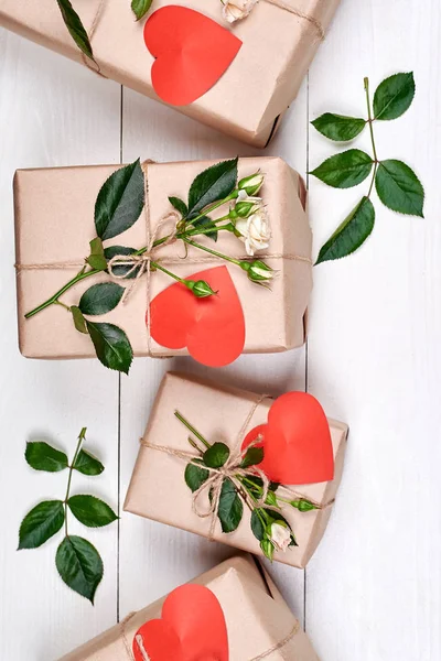 Hediye kutuları taze gül ve beyaz ahşap zemin üzerinde kırmızı kalpler. Kadının gün (8 Mart), Sevgililer günü, anneler günü için tebrik kartı, düz yatıyordu. Aşk kavramı. Tatil arka plan, satış, alışveriş