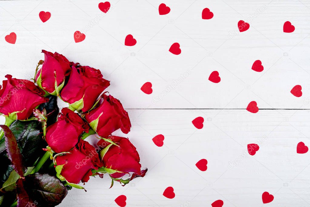 Top view bouquet of red roses and paper hearts on white wooden background, copy space. Greeting card mockup for Saint Valentines Day, Womans Day (March 8), Mothers Day. Love, wedding concept, flat lay