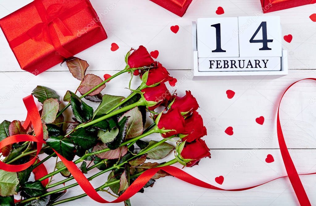 Valentines Day background with bunch of red roses, gift boxes, ribbon and wooden block calendar february 14 , copy space. Greeting card mockup. Love concept. Top view, flat lay