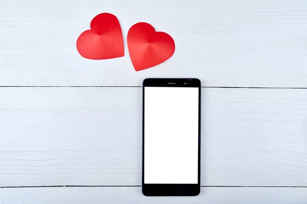 Bovenaanzicht van mobiele smartphone met witte leeg scherm en twee rode papier harten op houten achtergrond, kopie ruimte. Plat lag, top uitzicht. Valentijnsdag toepassingssjabloon mockup — Stockfoto