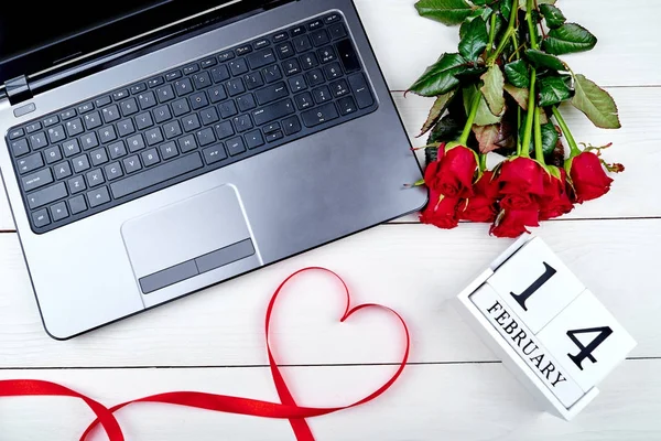 빨간 장미, 나무 달력 2 월 14 일, 심장 및 흰색 테이블에 오픈 랩톱 컴퓨터 모양 리본 부케의 최고 볼 수 있습니다. 발렌타인, 편평한 위치에 대 한 인사말 카드 — 스톡 사진
