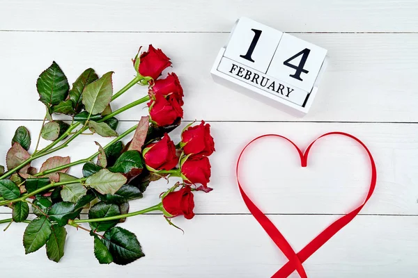 Día de San Valentín fondo con ramo de rosas rojas, cinta en forma de corazón y febrero 14 calendario bloque de madera, espacio de copia. Tarjeta de felicitación maqueta. Concepto de amor. Vista superior. Puesta plana —  Fotos de Stock