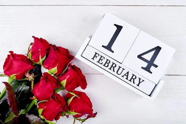 Closeup of bouquet of red roses and february 14 wooden block calendar, copy space for text. Greeting card mockup for Valentines Day. Top view — Stock Photo, Image
