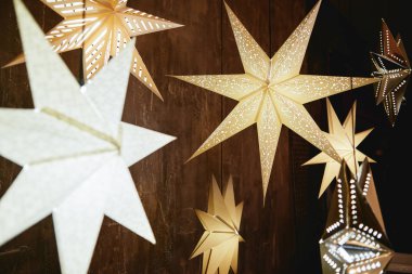 Decorative stars bulb lights on brown wood wall, copy space. Christmas background