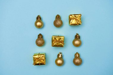 Altın parıltılı mücevherleri ve pastel mavi arka planda hediyeleri olan yaratıcı Noel deseni