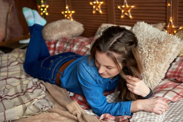 Mooie vrouw in jeans kleding liggend op bed — Stockfoto