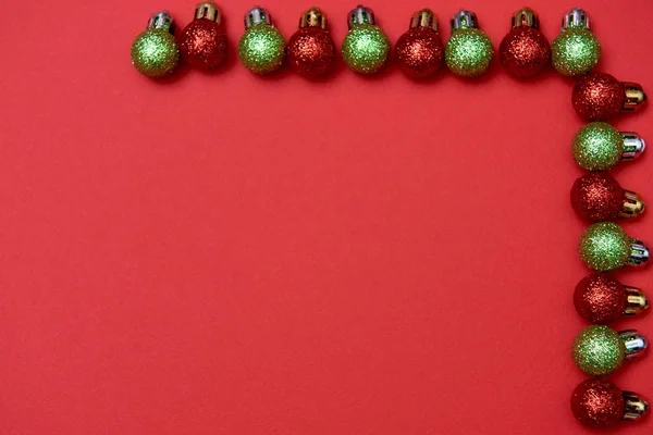 Creative Christmas pattern with red and green shiny baubles on red background