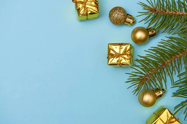 Kreatív karácsonyi minta arany fényes baubles, fenyő ágak és ajándékok pasztell kék háttér — Stock Fotó