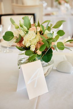 Güzel çiçek aranjmanı ve cam vazoda yeşillik.