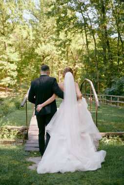 Parkta yürüyen genç gelin ve damadın boy portresi.