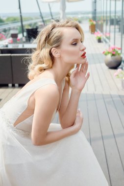 Güzel bir gelinin portresi, şık bir gelinlik ve açık hava saç stili.