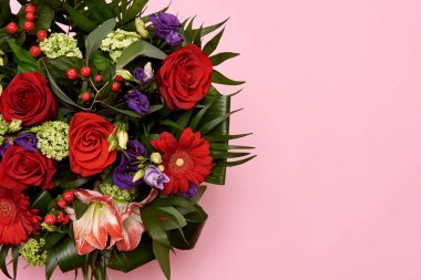 Pastel pembe arka planda güzel bir buket kırmızı ve mor çiçek.