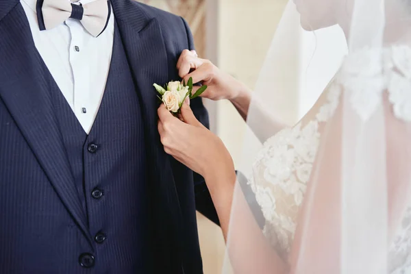 Närbild av bruden sätta på boutonniere till brudgummen smoking, snut — Stockfoto