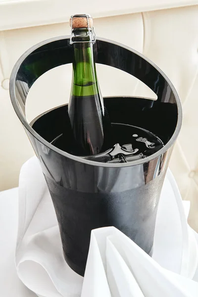 Bottle of cold wine or champagne in ice bucket on white table at — Stock Photo, Image
