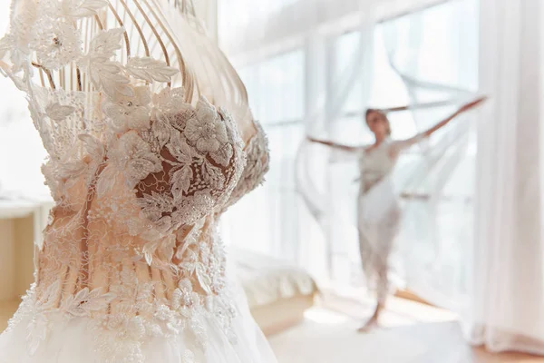 Luxe trouwjurk op hangers met bruid in wazig op achtergrond — Stockfoto