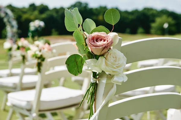 Flores de rosas frescas en sillas de madera blanca a cada lado del arco — Foto de Stock