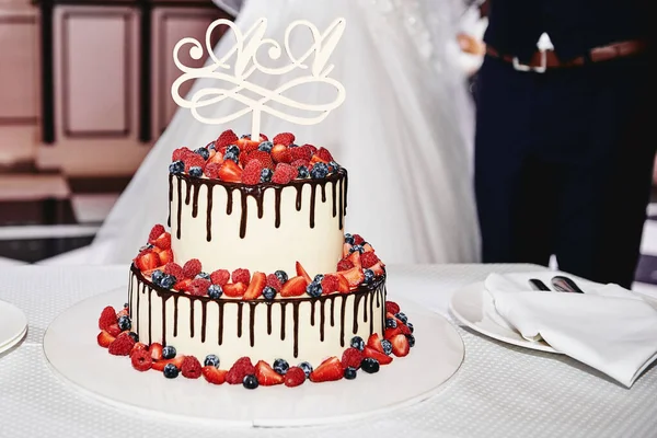 Elegant white wedding cake decorated with fresh berries and choc