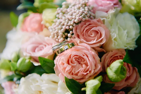 Close up of two golden wedding rings on bridal bouquet of pink a — Stock Photo, Image