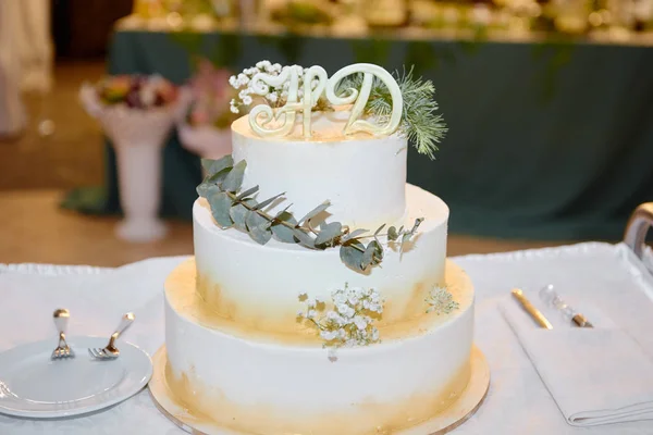 Elegant white wedding cake decorated with flowers, green leaves