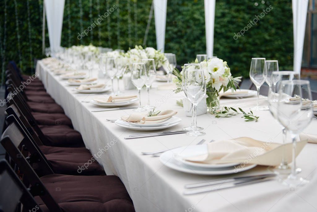 Table setting with sparkling wineglasses and cutlery at wedding reception outdoors