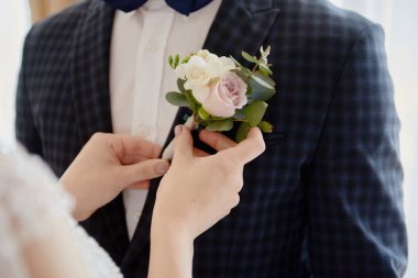 Gelinin yakını damadın smokinine yaka çiçeği takıyor, polis.