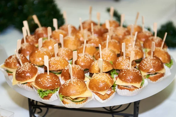 Buffet table with mini hamburgers at luxury wedding reception, c