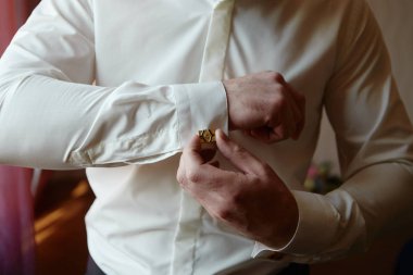 Lüks beyaz gömlek kolunun düğmelerini ilikleyen adam, kopyalama alanı. Damat pencerenin yanında duran kol düğmelerini düzeltir