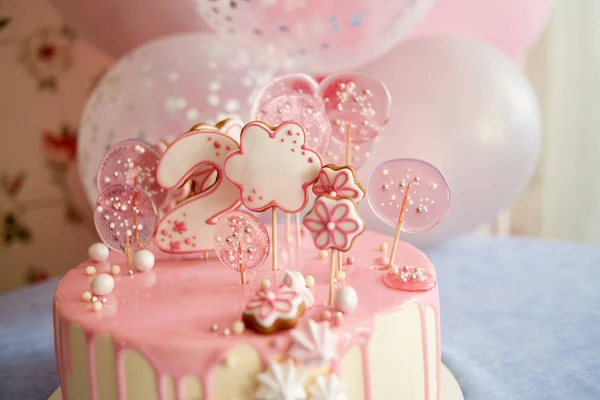 Round pink birthday cake decorated with lollipops, gingerbreads, flowers, beads number two on the top — 스톡 사진