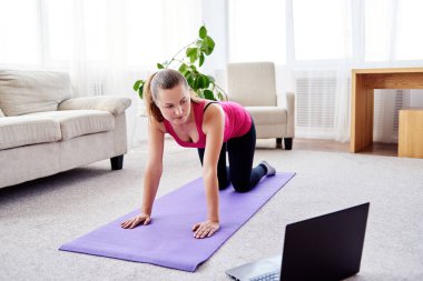 Güzel genç bir kadın evde egzersiz yapıyor.