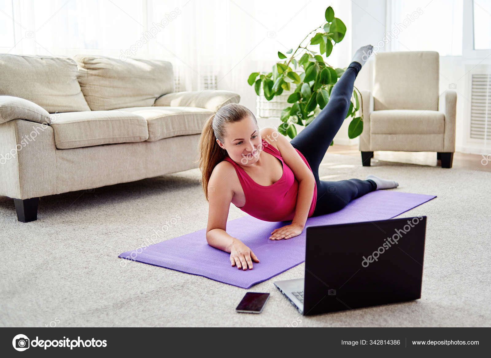 Beautiful young woman training online at home on laptop computer. Yoga ...