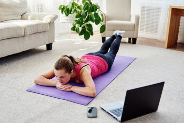 Dizüstü bilgisayarda, kopya alanı Eğitim Online egzersiz için sırt üstü yere vasıl ev, yapmak güzel ve genç birbayan. Tam uzunlukta portre. Çalışma dışarı egzersiz yoga, pilates,