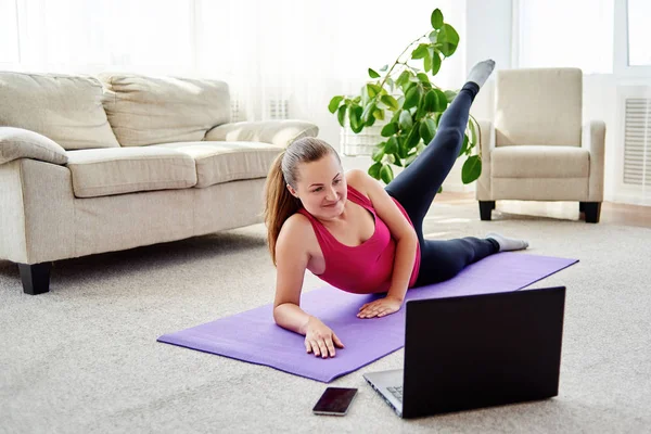 Bela jovem formação on-line em casa no computador portátil. Yoga, pilates, exercitando — Fotografia de Stock