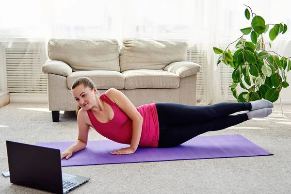 Piękna młoda kobieta trening online w domu na laptopie. Joga, pilates, ćwiczenie — Zdjęcie stockowe