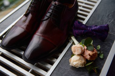 Kahverengi erkek ayakkabıları, papyon ve yaka çiçekleri, fotokopi alanı. Modern erkek aksesuarları. Düğün detayları