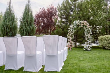 Düğün için bahçede bir yer, fotokopi odası. Kemerlerin her iki tarafında da çiçek ve beyaz sandalyelerle süslenmiş düğün kemeri. Düğün ayarları