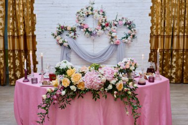 Restoranda düğün başkanlığı, fotokopi odası. Çiçekleri, yeşilliği, mumları ve pembe kumaşı olan yeni evliler için ziyafet masası. Çiçek aranjmanı. Lüks düğün dekorasyonu