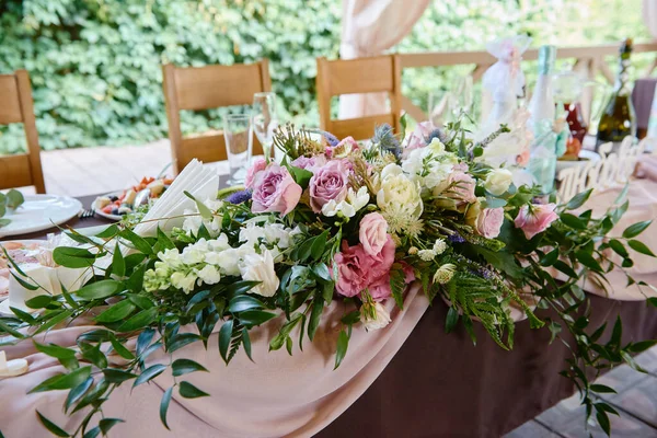 Üppige Blumenarrangements auf dem Hochzeitstisch im Freien. Hochzeitspräsidium im Restaurant, Kopierraum. Banketttisch für Frischvermählte mit rosa und lila Rosenblüten. Luxus-Hochzeitsdekoration — Stockfoto