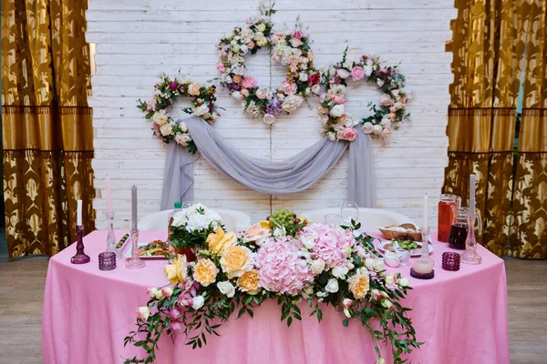 Bröllopspresidium i restaurang, kopieringsutrymme. Bankettbord för nygifta med blommor, grönska, ljus och rosa trasa. Sköna blomsterarrangemang. Lyxig bröllopsinredning — Stockfoto